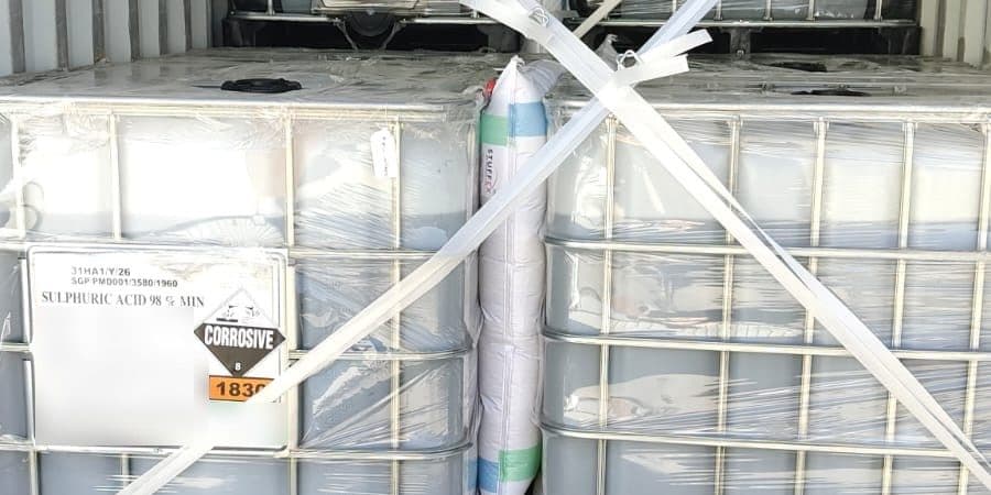 IBCs of sulphuric acid 98% with Class 8 corrosive and UN 1830 labels, strapped inside a shipping container